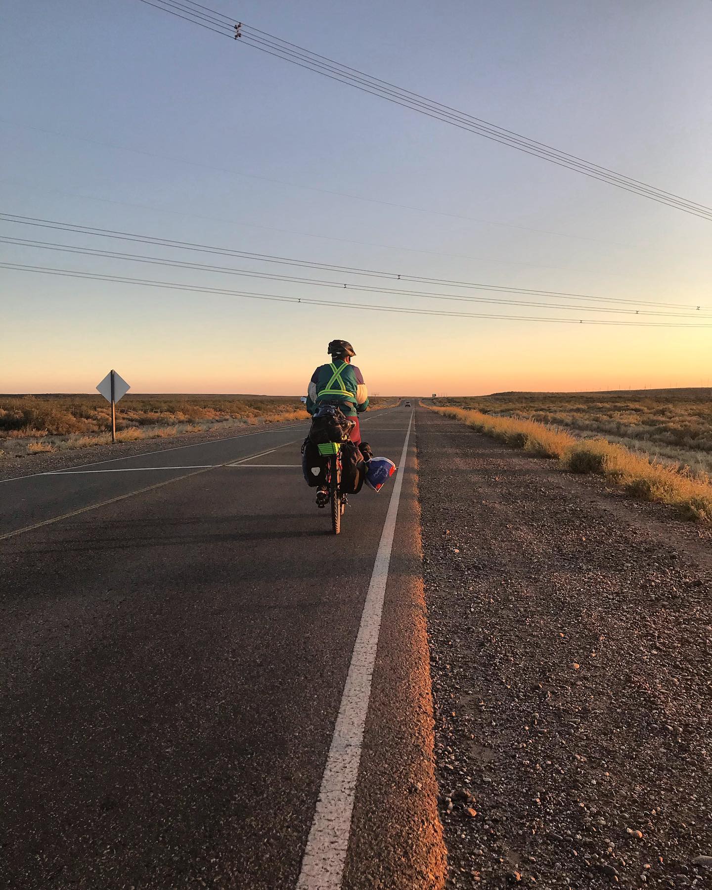 Ciclista de expedición en carretera infinita al atardecer