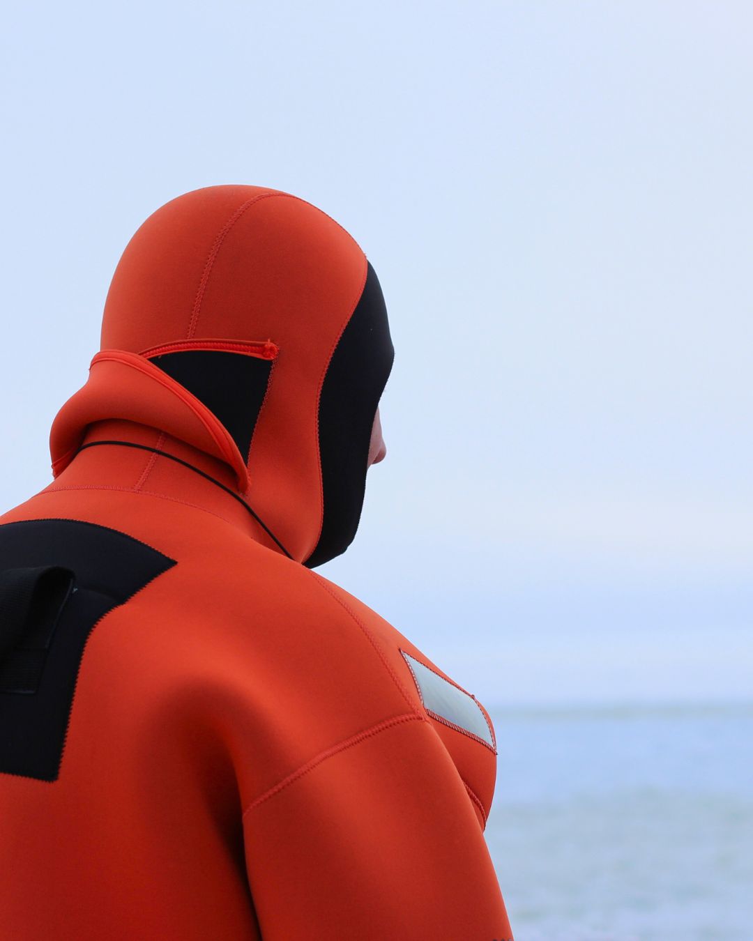 Traje de inmersión ártica naranja frente al mar helado