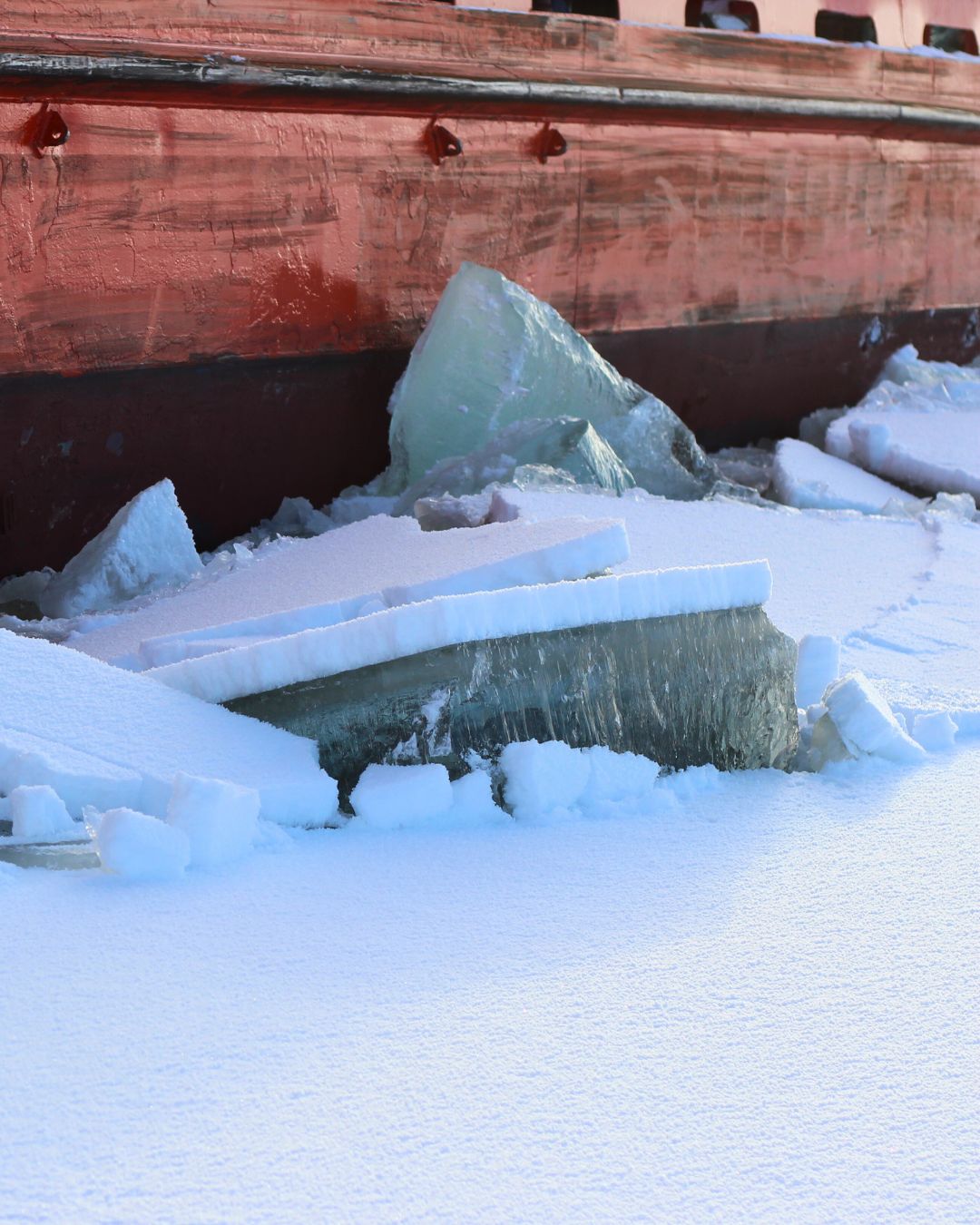 Bloques de hielo junto al casco de un barco rojo en el Báltico